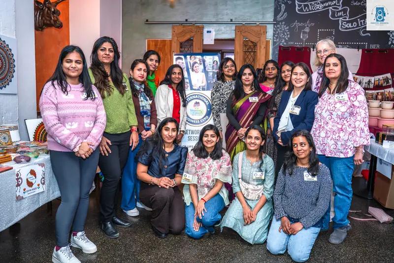 A group of women pose together for a photo indoors near market stalls, smiling at the camera.